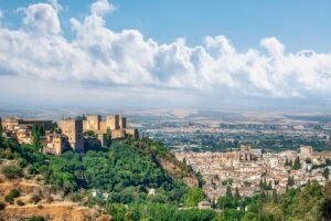 pexels-photo-14688077-14688077 A scenic view of the historic Alhambra in Granada, Spain, surrounded by lush greenery and an expansive cityscape.